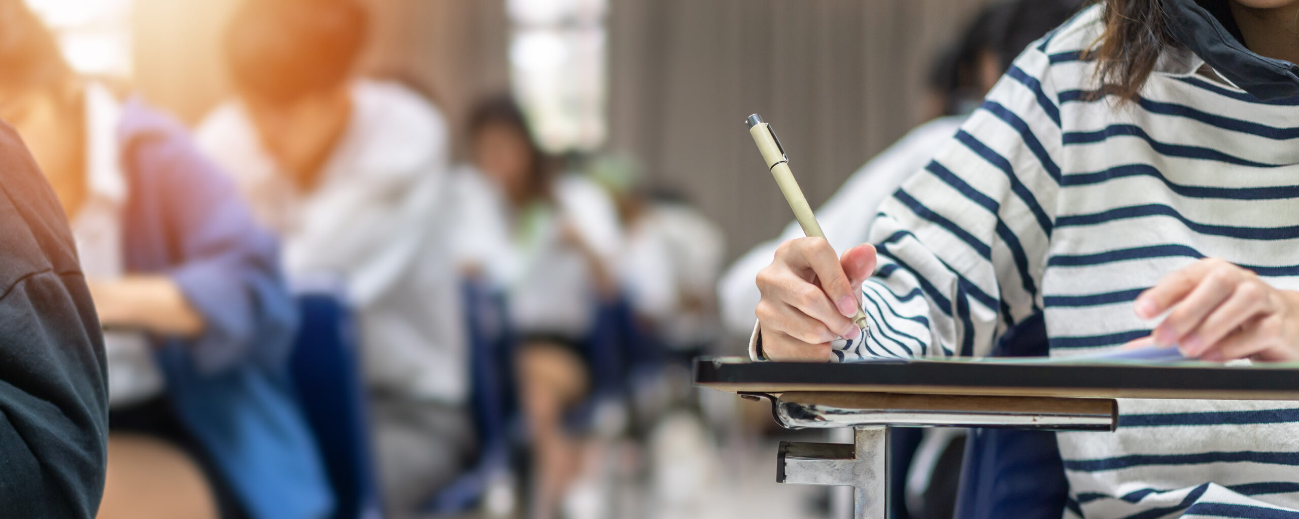 Zbliżenie na rękę studenta piszącego na kartce podczas egzaminu.